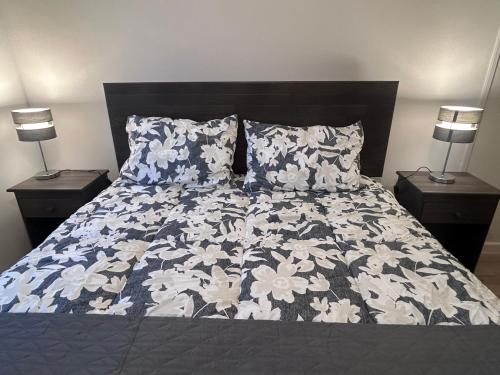 a bed with a blue and white comforter and two lamps at 2 ambientes, cómodo y central in Puerto Montt
