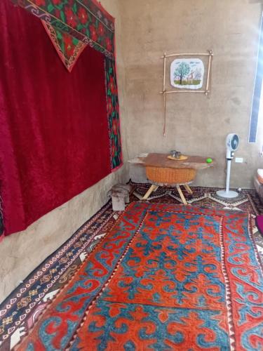 a room with a table and a red curtain and a rug at Japar in Bokonbayevo