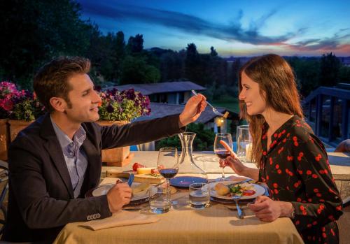 a man feeding a woman a glass of wine at a table at Agriturismo Valle del Marta in Tarquinia