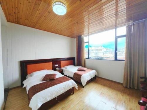 a bedroom with two beds and a large window at Mount Emei Fulin Hotel in Baoguosi