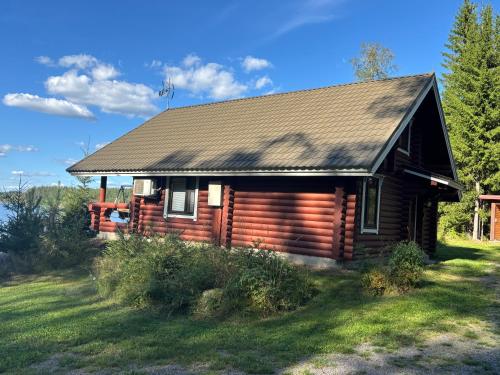 a log cabin in a field next to a house at Saimaa Raikala in Vuoriniemi