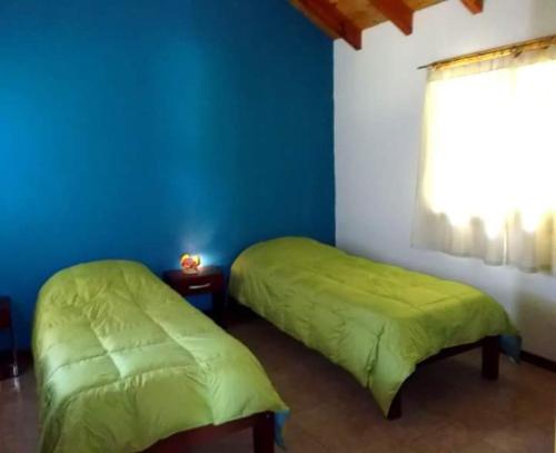 2 camas en una habitación con una pared azul en Cautiva Morena en San Martín de los Andes