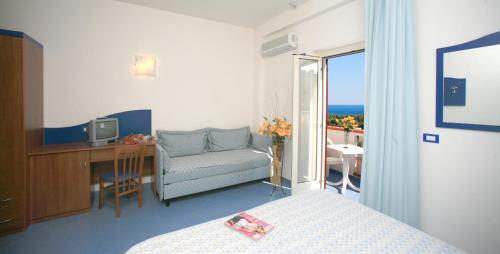 a bedroom with a bed and a desk and a chair at Albergo Godenizzo in Peschici