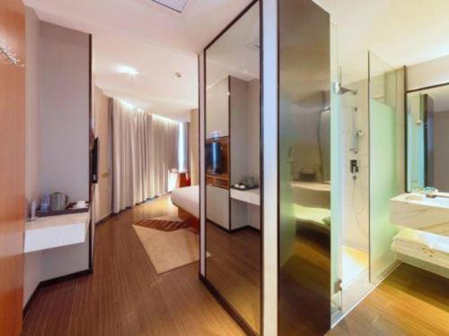 a bathroom with a large glass shower and a bedroom at Borrman Hotel Zhanjiang Xuwen Port Terminal in Xuwen
