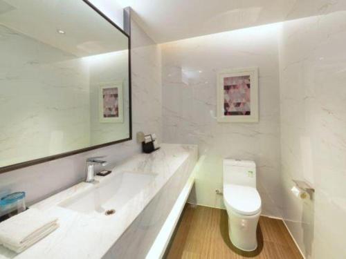a white bathroom with a toilet and a sink at Borrman Hotel Zhanjiang Xuwen Port Terminal in Xuwen