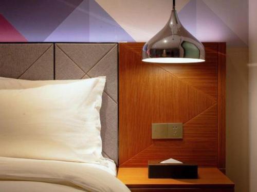 a bedroom with a bed and a light and a night stand at Borrman Hotel Zhanjiang Xuwen Port Terminal in Xuwen