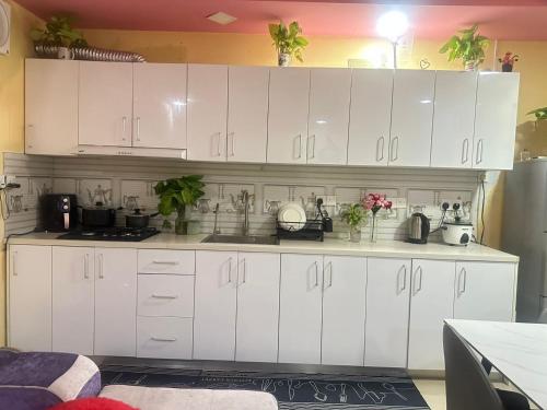 a kitchen with white cabinets and flowers on the counters at Violetfehi Homestay in Fuvahmulah