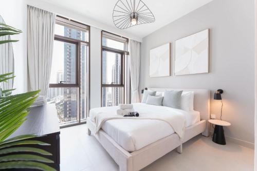 a white bedroom with a large bed and large windows at Free housekeeping visits during your stay - StayShort - Creek Harbour Sleeps 4 Perfect for Nature Lovers in Dubai