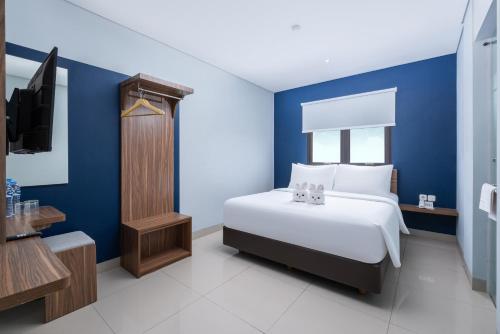 a bedroom with blue walls and a bed and a tv at Gold Hotel Simpang Lima in Semarang
