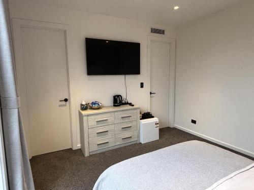 a bedroom with a bed and a television on a wall at Cozy Ensuite in Auckland