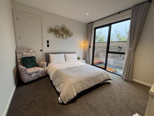 a bedroom with a bed and a chair and a window at Cozy Ensuite in Auckland