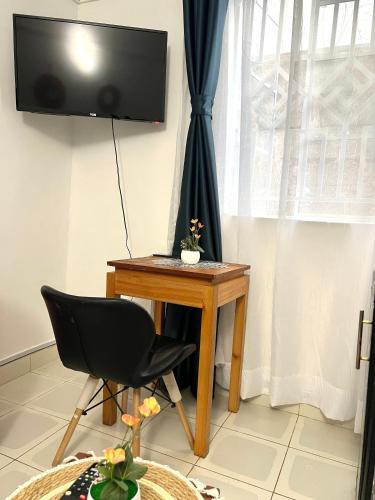 a desk with a chair and a television on a wall at Urban studio Milimani in Kisumu