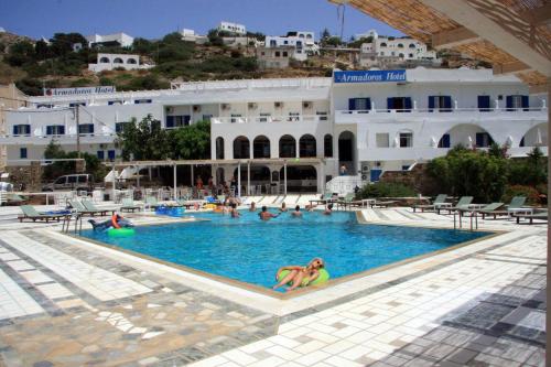 a woman in a swimming pool in front of a hotel at Armadoros Hotel / Ios Backpackers in Ios Chora
