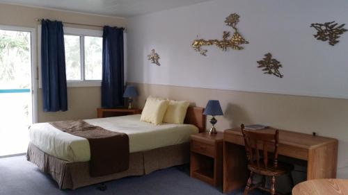 a bedroom with a bed and a desk and a window at AppleTree Inn in Radium Hot Springs