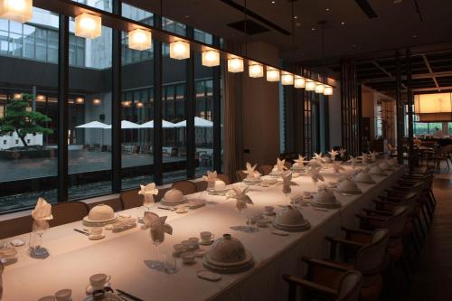 a long table with plates and cups on top of it at PERNULO Hotel Fuzhou in Fuzhou