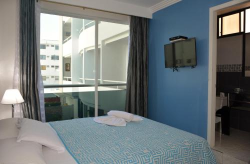 a blue bedroom with a bed and a tv at Hotel Casablanca Salinas in Salinas