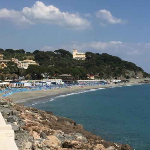 a beach with a bunch of people in the water at Hotel Flora in Celle Ligure