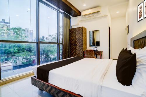 a bedroom with a large bed and a large window at Super Collection O Sanpada Railway Junction in Turambhe