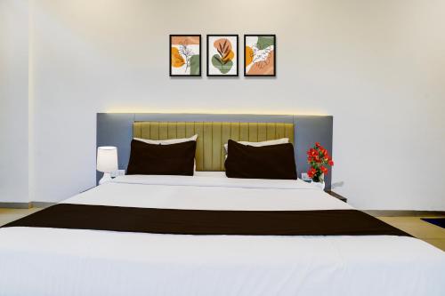 a bedroom with a large white bed with black pillows at Super Collection O Sanpada Railway Junction in Turambhe