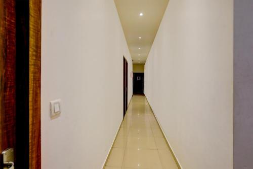 a hallway with white walls and a tile floor at Super Collection O Sanpada Railway Junction in Turambhe