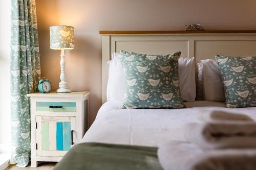 a bedroom with a bed with pillows and a lamp at Betony in Bamburgh
