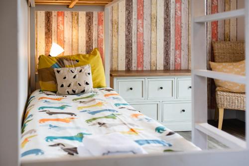 a small bedroom with a bed with a striped wall at Betony in Bamburgh