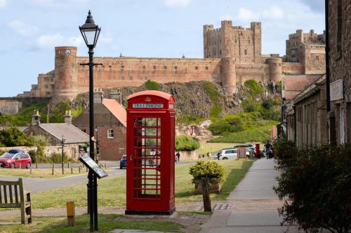 a red phone booth in front of a castle at Betony in Bamburgh