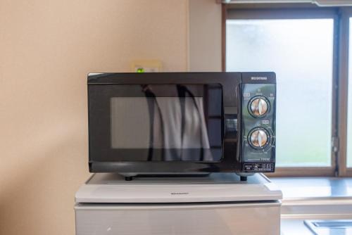a microwave sitting on top of a refrigerator at 長野県上田市 最大15名 1棟貸し切り in Ueda