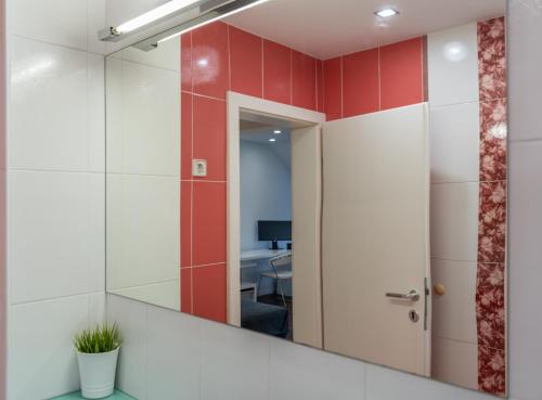 a mirror in a bathroom with red and white tiles at Celje Center Apartment in Celje