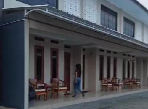 a woman walking in front of a building at Family Guest House in Sumedang Utara