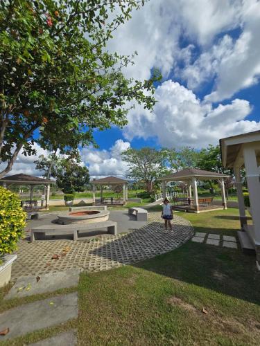 a woman standing in a park with benches and trees at Beautiful four bedroom home in Talisay