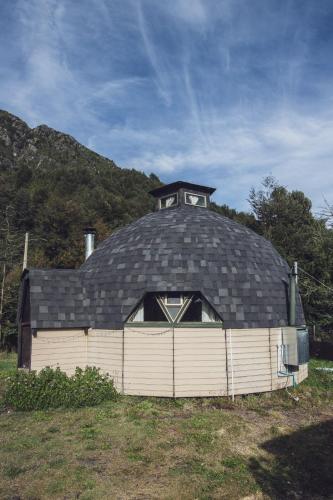 a large black roofed building with a window at Domo Osiris a 10 minutos de termas Vergara in Coñaripe