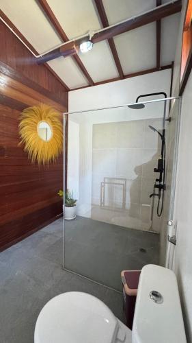 a bathroom with a toilet and a glass shower at La Bima Beach House in Sekongkang Bawa