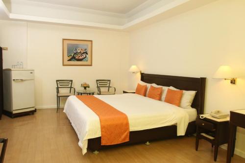 a hotel room with a large bed with orange pillows at Harbor Town Hotel in Iloilo City