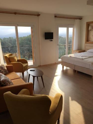 a bedroom with a bed and a couch and chairs at Clementin Suits Sigacık in Siğacık