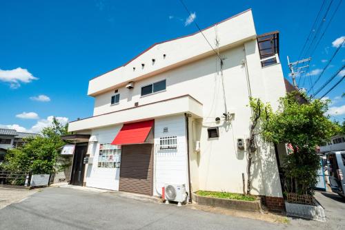a white building with a red sign on it at 大和の宿 Kitabukuro202 in Nara