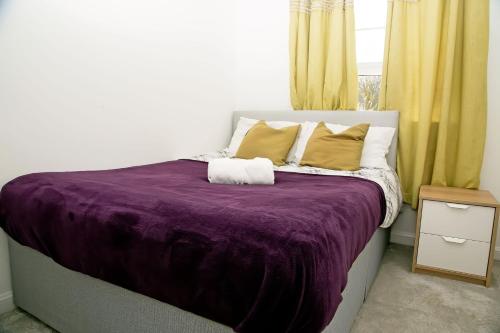 a bedroom with a purple bed with yellow curtains at Unbeatable Value I Best Rates I Garden I Wi-Fi I Parking in Stanford le Hope