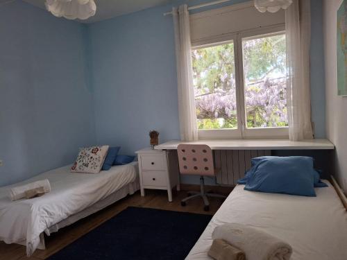 two beds in a room with a window and a desk at Caldetas in Caldes d'Estrac