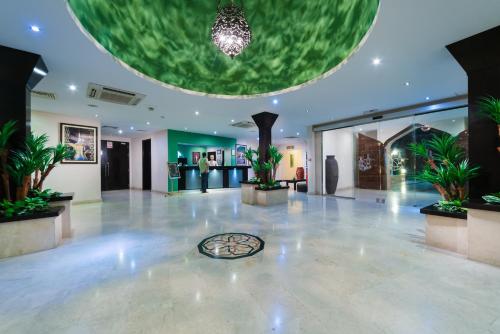 a lobby with a large room with potted plants at Al Wadi Hotel in Sohar