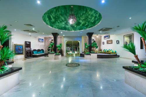 a lobby with potted plants and a green ceiling at Al Wadi Hotel in Sohar
