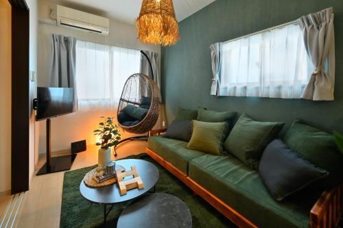 a living room with a green couch and a table at Otter Stay - Masaki in Nagoya