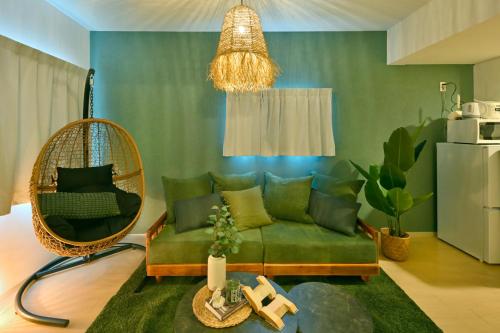 a living room with a green couch and a rattan chair at Otter Stay - Masaki in Nagoya