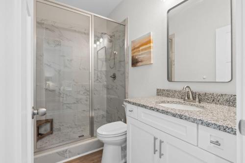 a white bathroom with a shower and a toilet at The Sea Salt Sandcastle in St. George Island