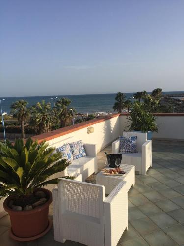 a balcony with white chairs and a table and the ocean at L'Approdo in San Leone