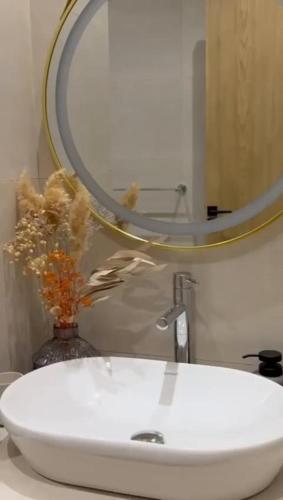 a bathroom sink with a mirror and a vase with flowers at Villa Ghalya in Al Maqārisah