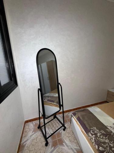 a mirror on a stand next to a bed at شقة كبيرة فيها 3 غرف و صالون مطبخ حمام و في شارع راقي في طنجة دار تونسي in Tangier