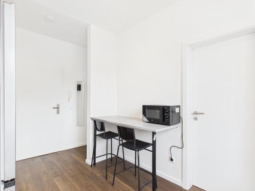 a kitchen with a table with two stools and a microwave at FlexiFlats in Lingen