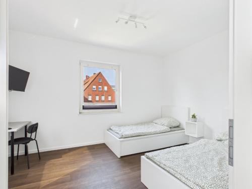 a white room with two beds and a desk at FlexiFlats in Lingen