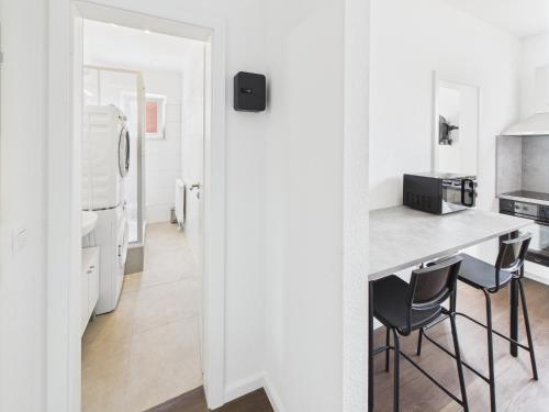 a kitchen with white walls and a counter and chairs at FlexiFlats in Lingen