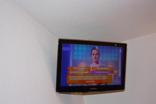 a television on a wall with a woman on it at Hôtel Quick Palace Valence Nord in Bourg-lès-Valence